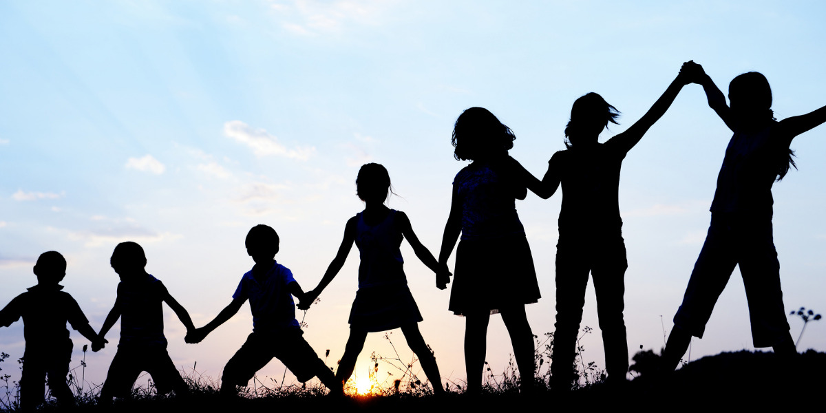 Silhouettes of children holding hands in a field.