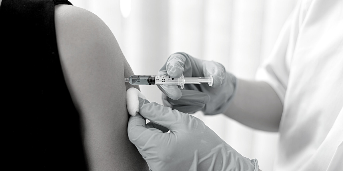 Person injecting another person in the top of the arm.