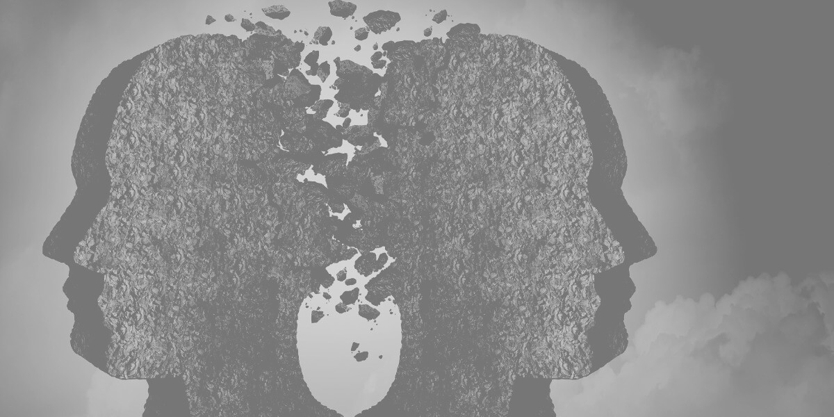 Greyscale cartoon image of two heads back to back crumbling away.