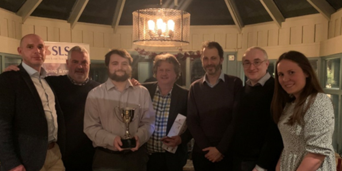Group of Gordons employees pictured in a pub with one holding a trophy.