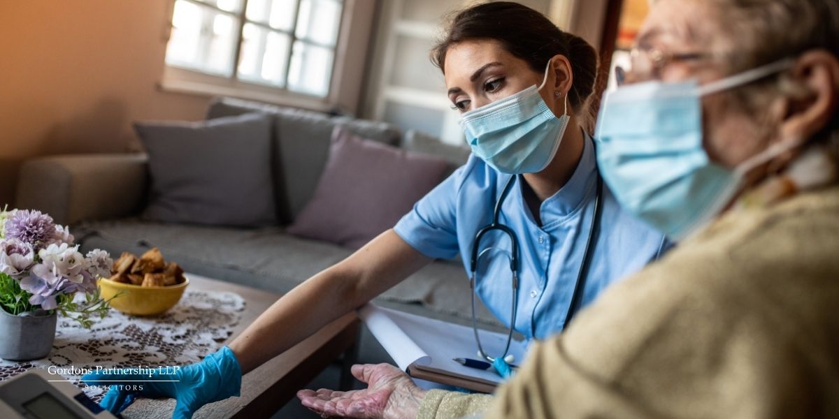 Nurse with mask on in a home with an old man.