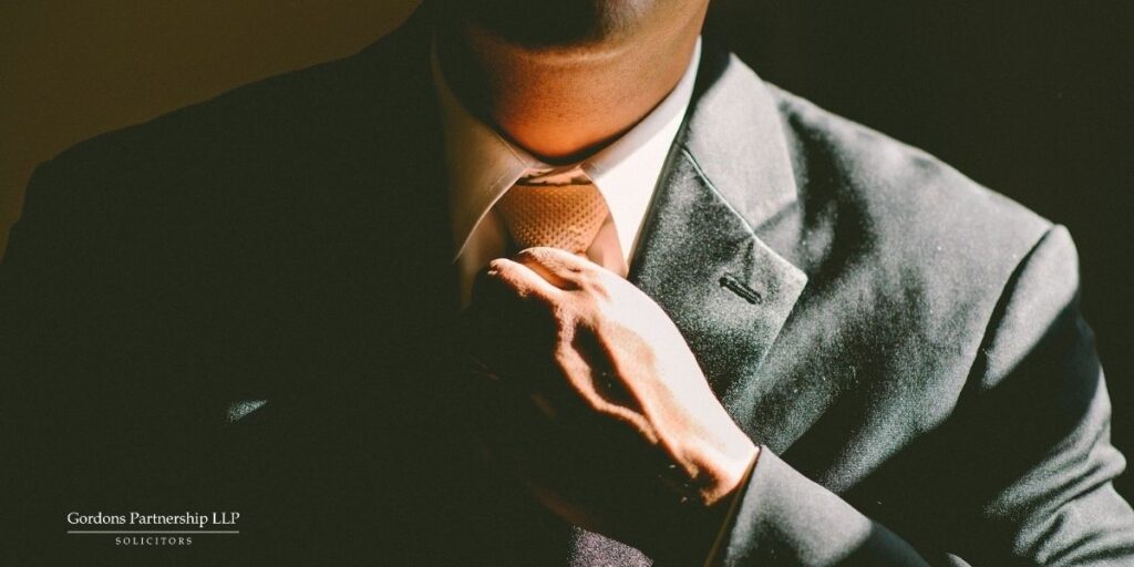 Man in a suit straightening his tie.