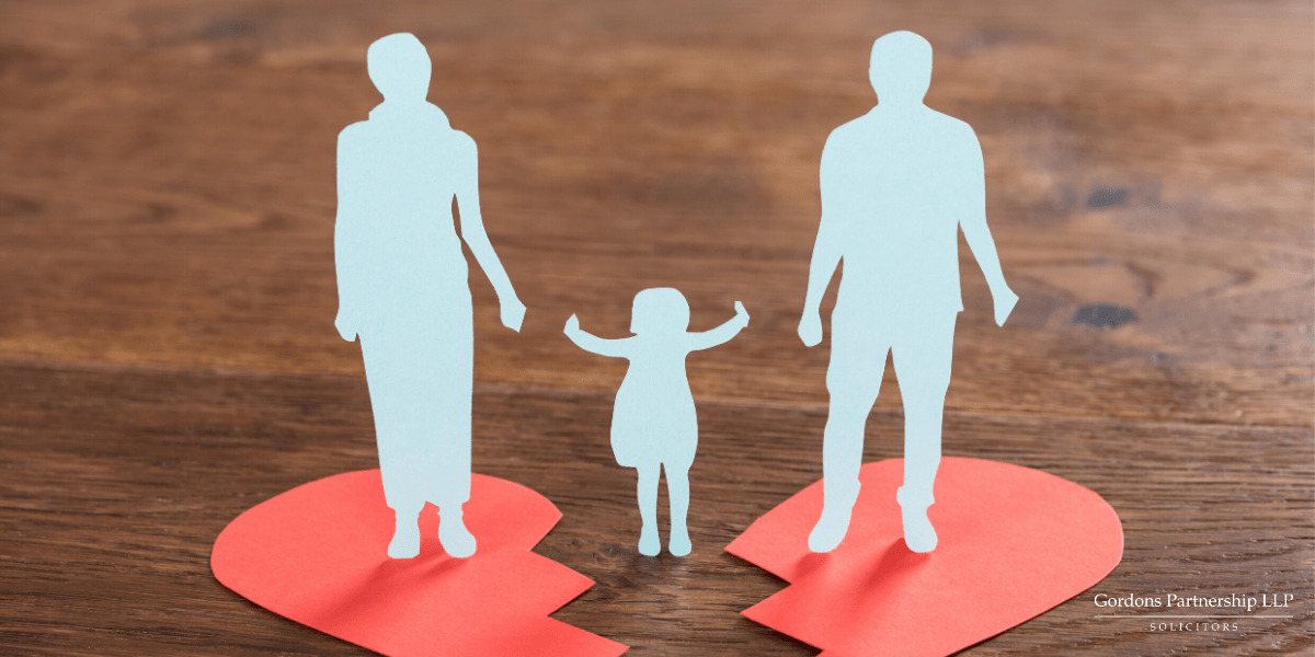 Paper cut out of a child in the middle of two parents during a divorce.