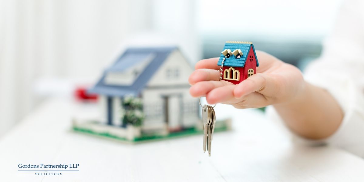 Holding a small model house with keys attached