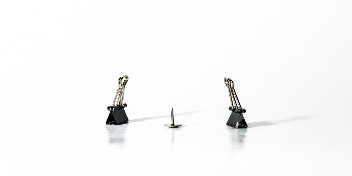 Two clipboard clips and a tack.