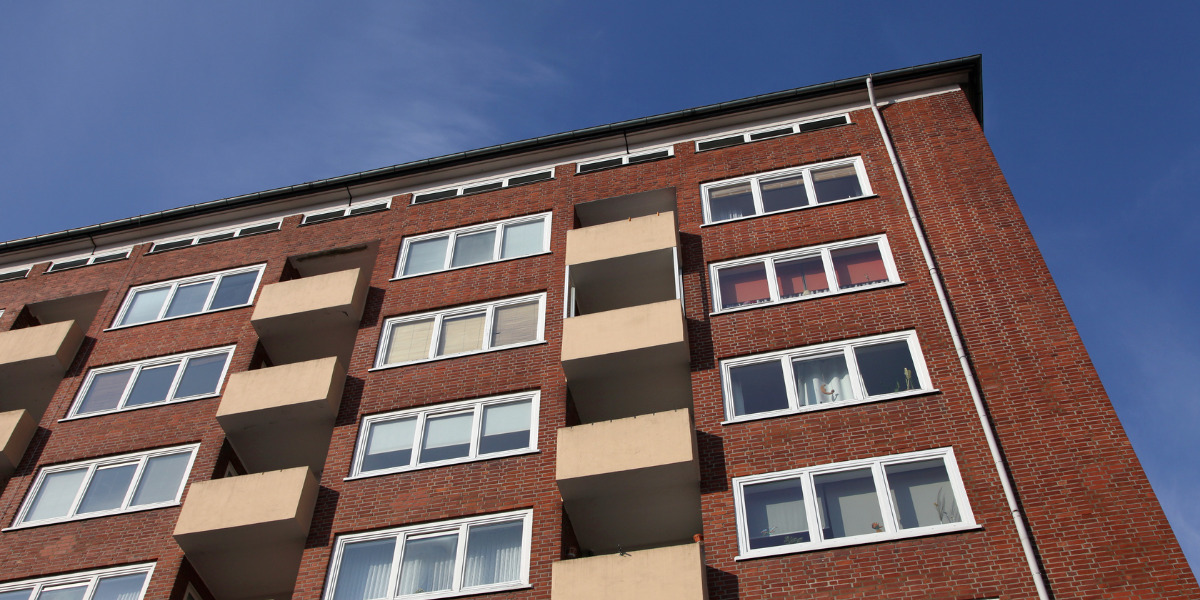 Low-angle view of a modern brick apartment building against a clear blue sky.