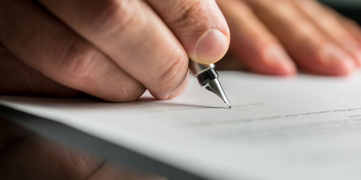 A focused individual signing a document with a fountain pen.