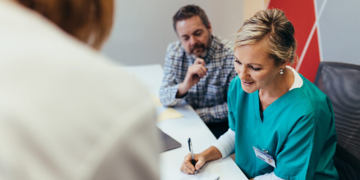 Two healthcare professionals attentively listening to a patient during a consultation.
