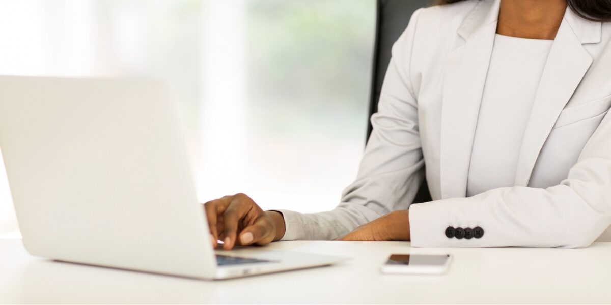 Professional at work: a focused individual in business attire working diligently on a laptop with a smartphone within easy reach.