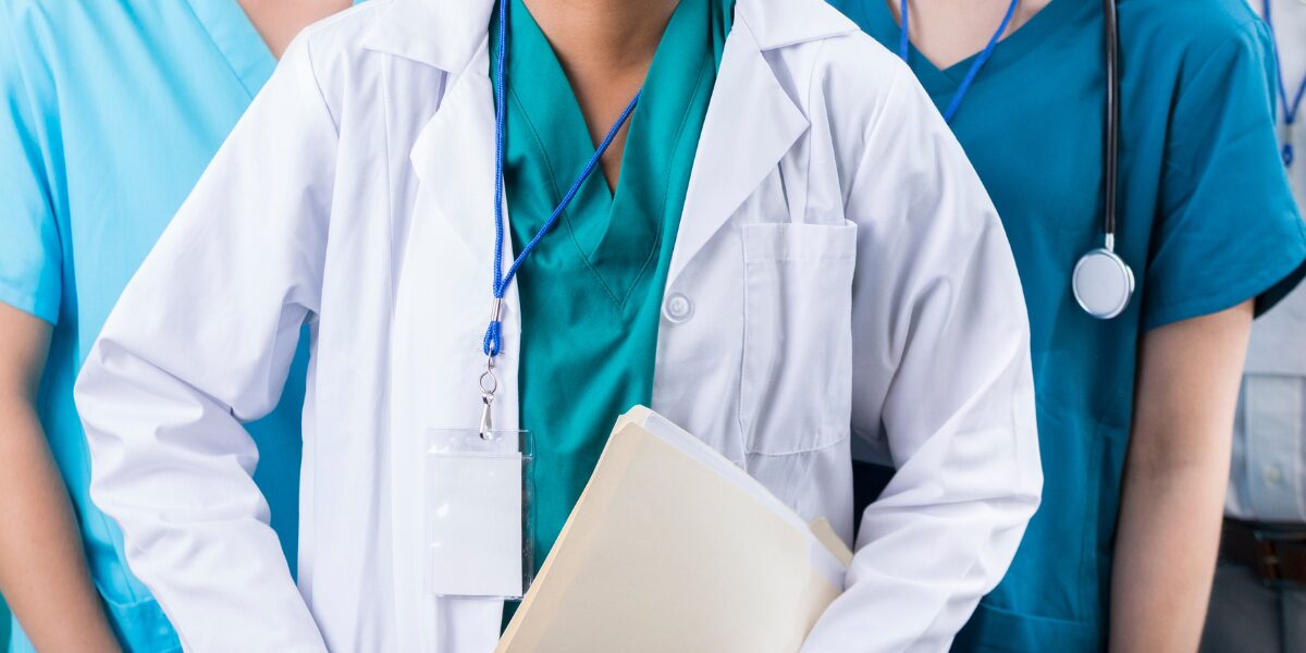 A group of medical professionals standing together, with one in focus holding a clipboard, showcasing teamwork in healthcare.