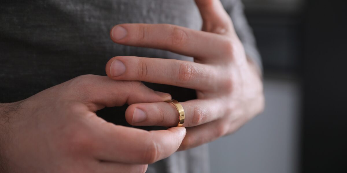 A person fidgeting with a gold wedding band on their ring finger, possibly signifying nervousness or deep thought.
