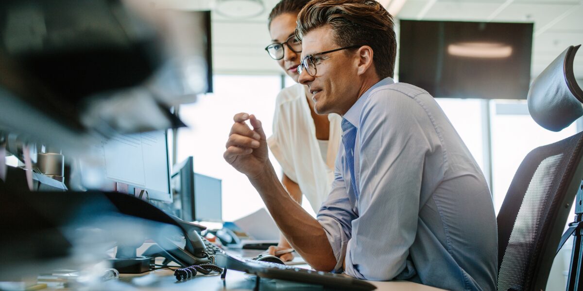 Two professionals engaged in a computer task within an office, exploring the new CQC portal.